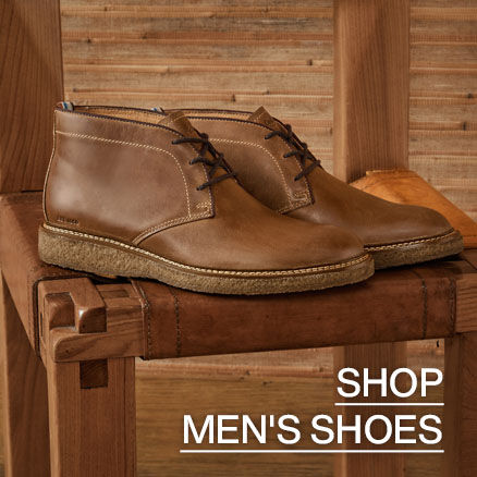 Pair of light brown men's cukka boots sitting on a natural wood colored chair. Click through to Shop Men's Shoe's.